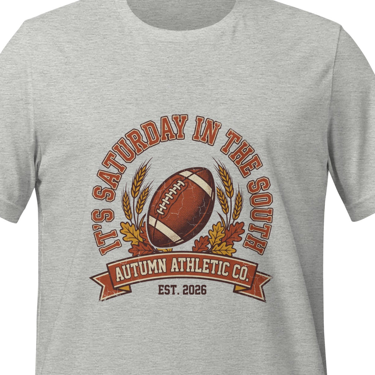 Athletic heather unisex t-shirt printed with a vintage arched badge reading It's Saturday in the South, curving over a football with wheat stalks and autumn leaves