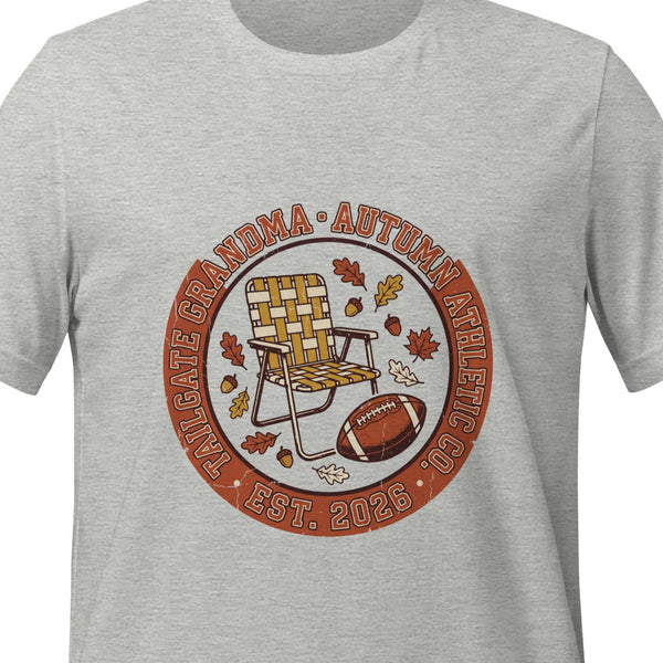 Athletic heather unisex t-shirt printed with a circular badge reading Tailgate Grandma and Autumn Athletic Co., arched around a folding lawn chair, a football and autumn leaves
