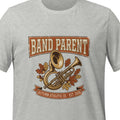 Athletic heather unisex t-shirt printed with a vintage banner reading Band Parent above a marching band tuba and trumpet, surrounded by autumn leaves in rust and gold